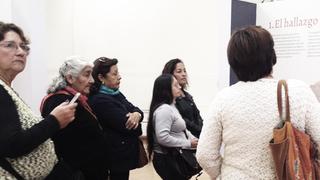 Grupo de mujeres mirando un panel en una exposición.