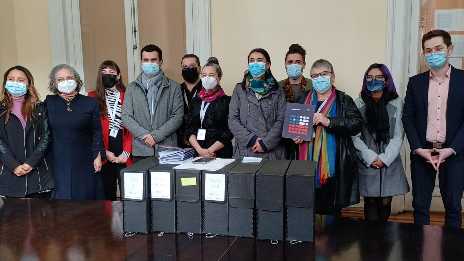 Grupo de gente detras de una mesa en la que hay varias cajas de archivo.