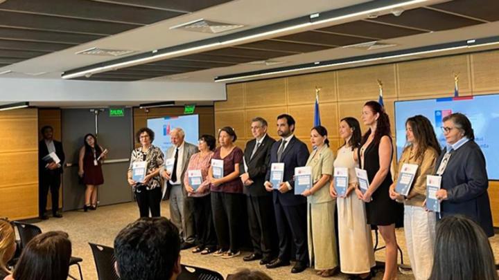 Autoridades en un escenario con libros en sus manos.