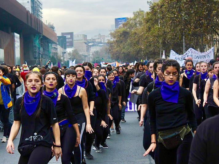 Universitarias marchando en la Alameda con pañuelos morados en el cuello.