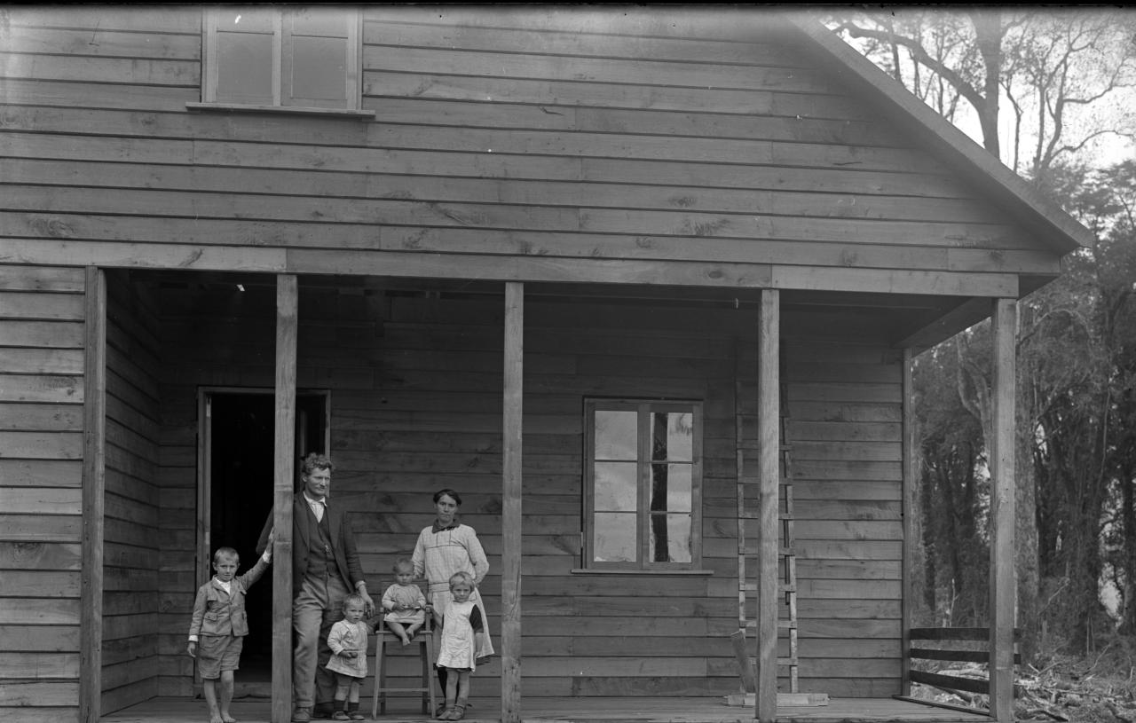 Familia frente a una casa de mdera.