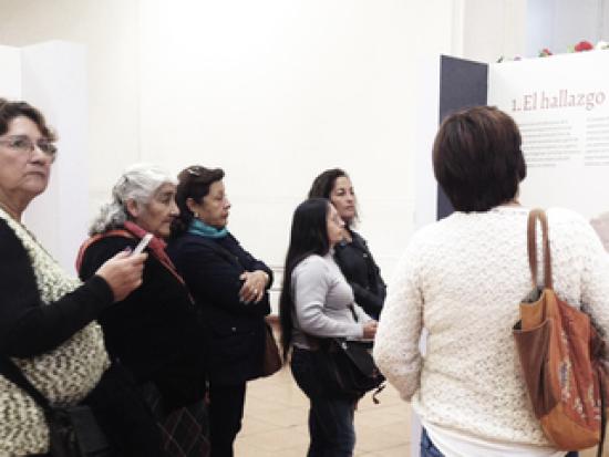 Grupo de mujeres mirando un panel en una exposición.