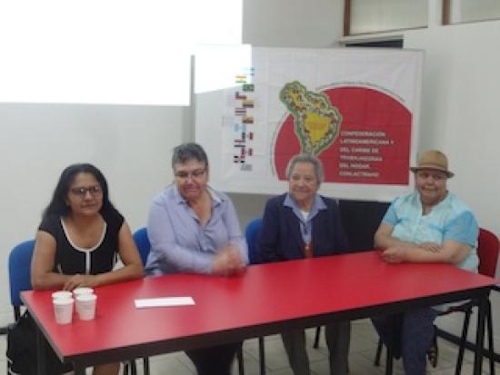 Mujeres en una mesa  rectangular roja dando una charla.