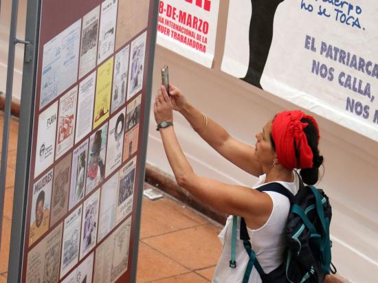 Mujer joven tomando una foto a un panel de la exposición.Exposicón en la