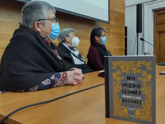 Tres personas en una  mesa con micrófonos y en primer plano un libro.