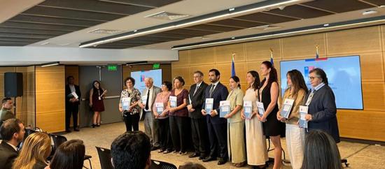 Autoridades en un escenario con libros en sus manos.