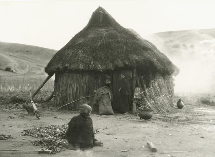 Mujer frente a una ruca mapuche.