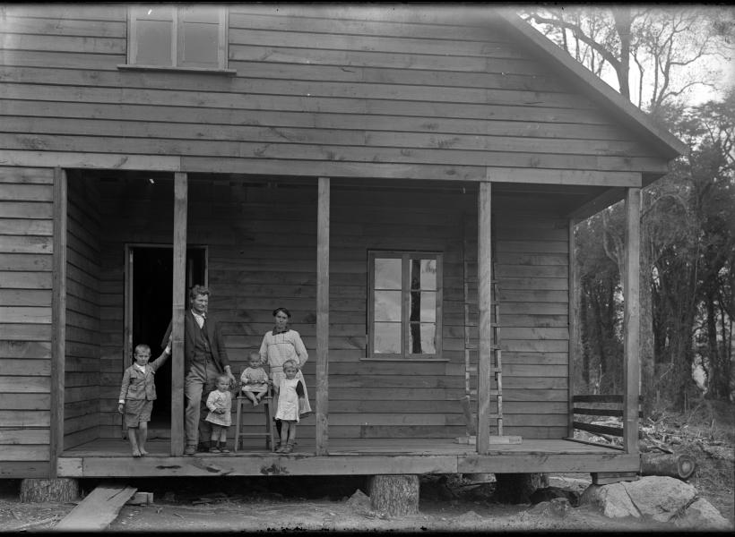 Familia frente a una casa de mdera.